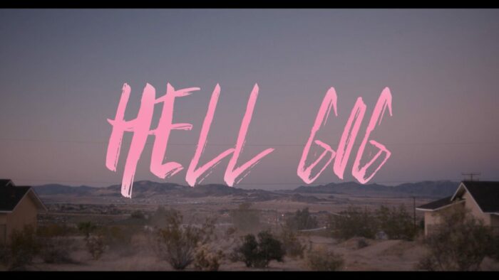 Title card for Hell Gig, pink text spells "Hell Gig" overlayed on an empty desert
