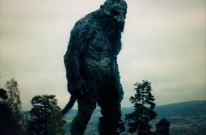 A colossal bearded troll stands taller than the trees in the surrounding forest in the 2022 Norwegian horror film Troll