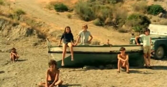 A group of children surrounding a fishing boat stare intensely at the camera