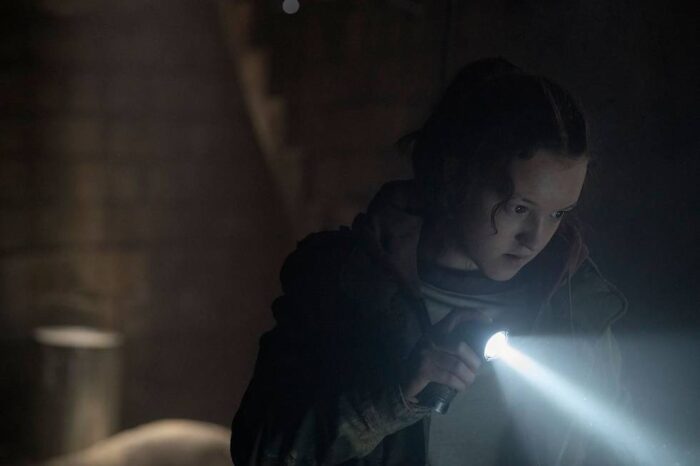 Ellie holds a flashlight toward something off camera right in The Last of Us S1E3 "Long Long Time"