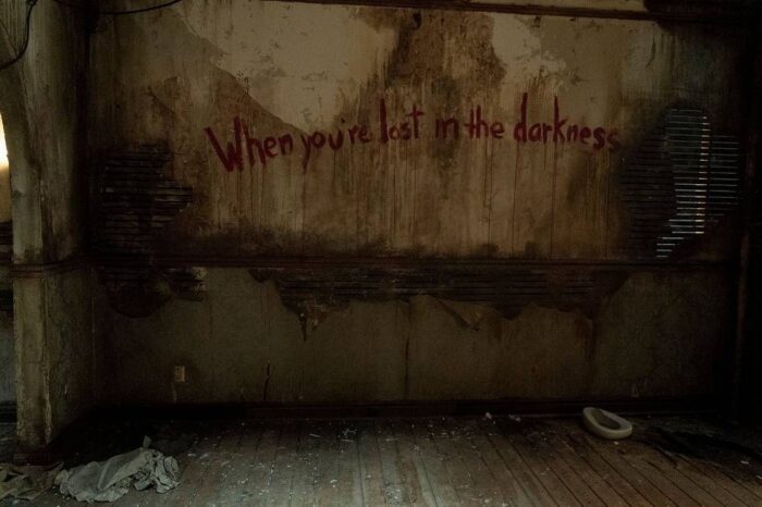 A wall that says "When you're lost in the darkness" on it. 