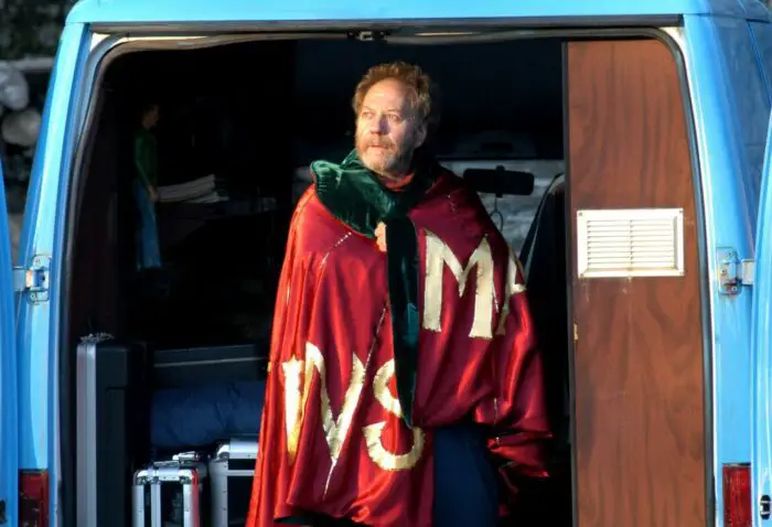 Bartel stand in the doorway of Marc's van wearing a red cape in Calvaire