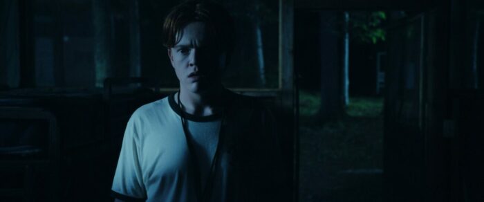 Ben stands in a dark cabin in She Came from the Woods