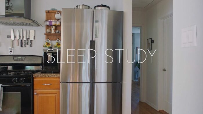 Title card for Sleep Study, white text spells "Sleep Study" overlayed on a still of a brightly lit kitchen