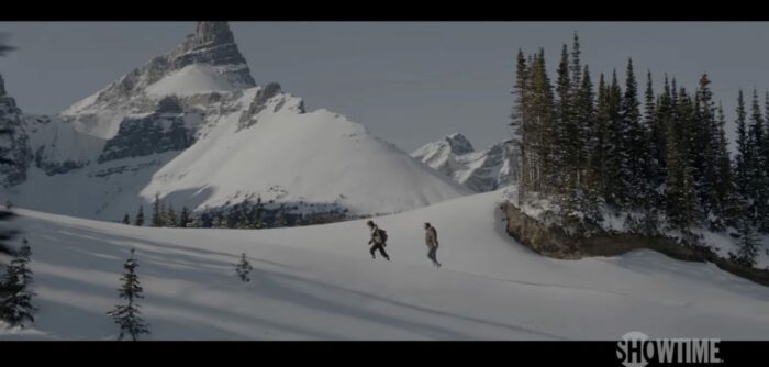 Two figures walk across a frozen wilderness