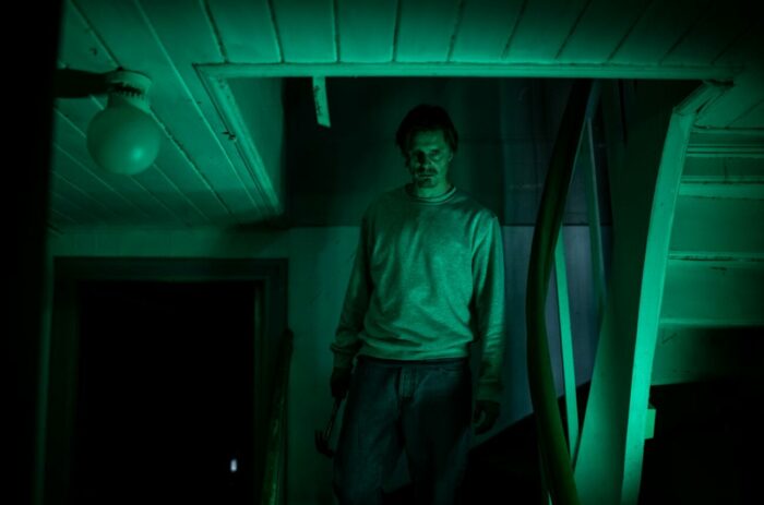 Kristian, Hunter's father, is seen walking downstairs in a green tinted room.