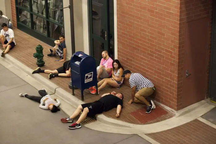 People lie on the ground outside of a building, looking as if injured.