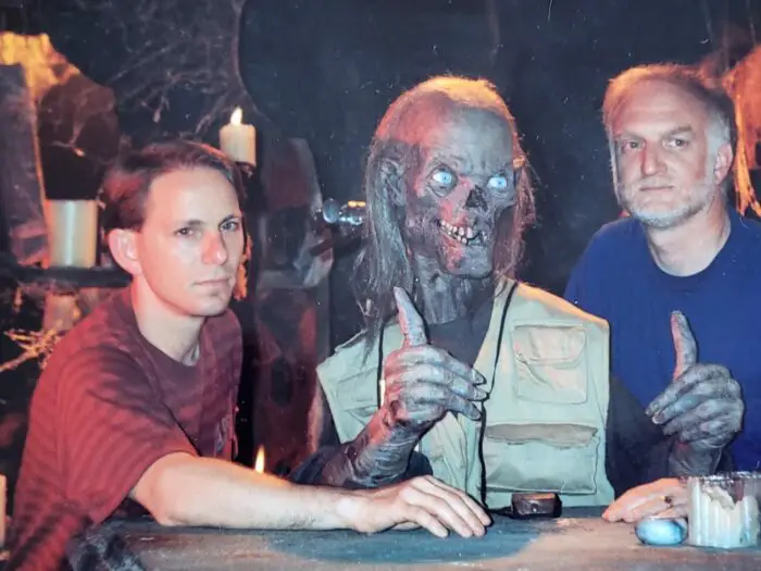 A L Katz stands on the left of Tale from the Crypt's Cryptkeeper and Gil Adler stands on the right. Both will attend CFF23