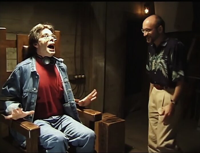 Stephen King looks shocked, sitting in an electric chair next to Green Mile director Frank Darabont