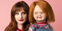 Director Kyra Gardner stands staring at Chucky, while wearing the same clothes.