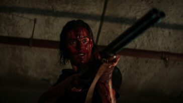 A blood-soaked woman with a shotgun