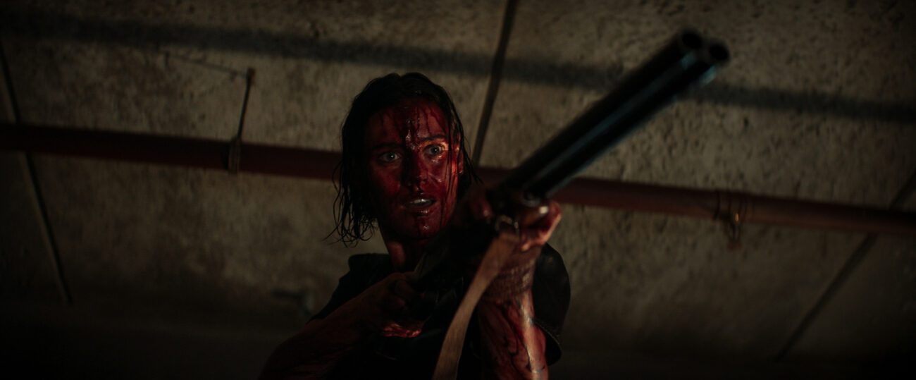 A blood-soaked woman with a shotgun