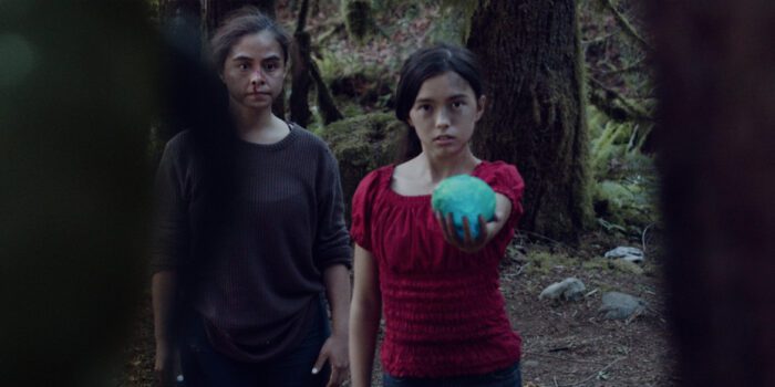 Maria holds out the blue goopy egg to the creature in the woods