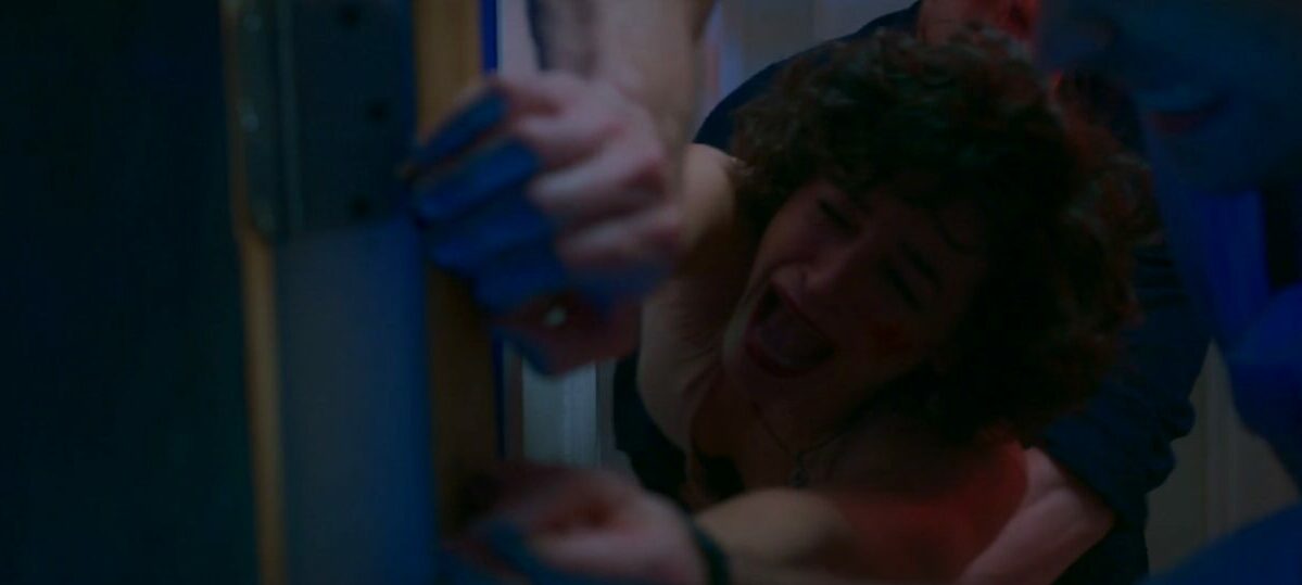 Mary hangs onto a doorway being pulled off of it by Brad and her hands being un clenched by Tony