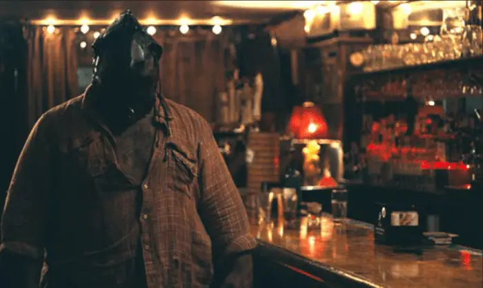 A man in a leather mask stands beside the bar in a pub in Poundcake