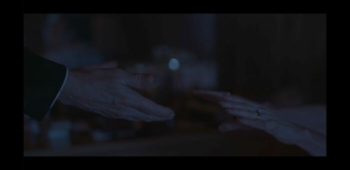 two hands reach out toward one another in the dark