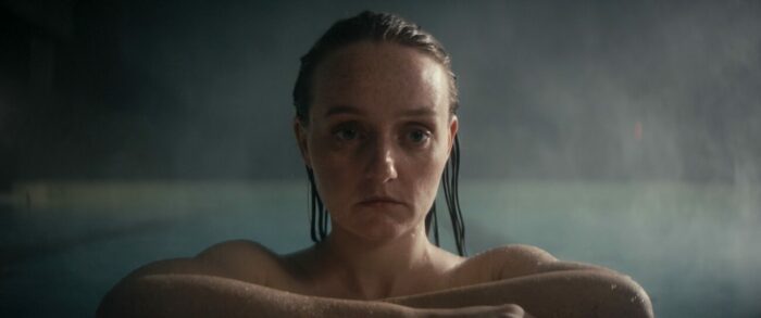 A woman stands in a pool with her arms folded on the edge