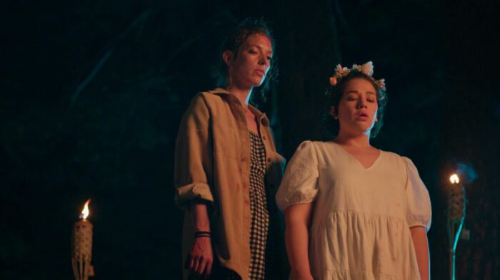 two women standing together in the night, one wearing a headband made of flowers