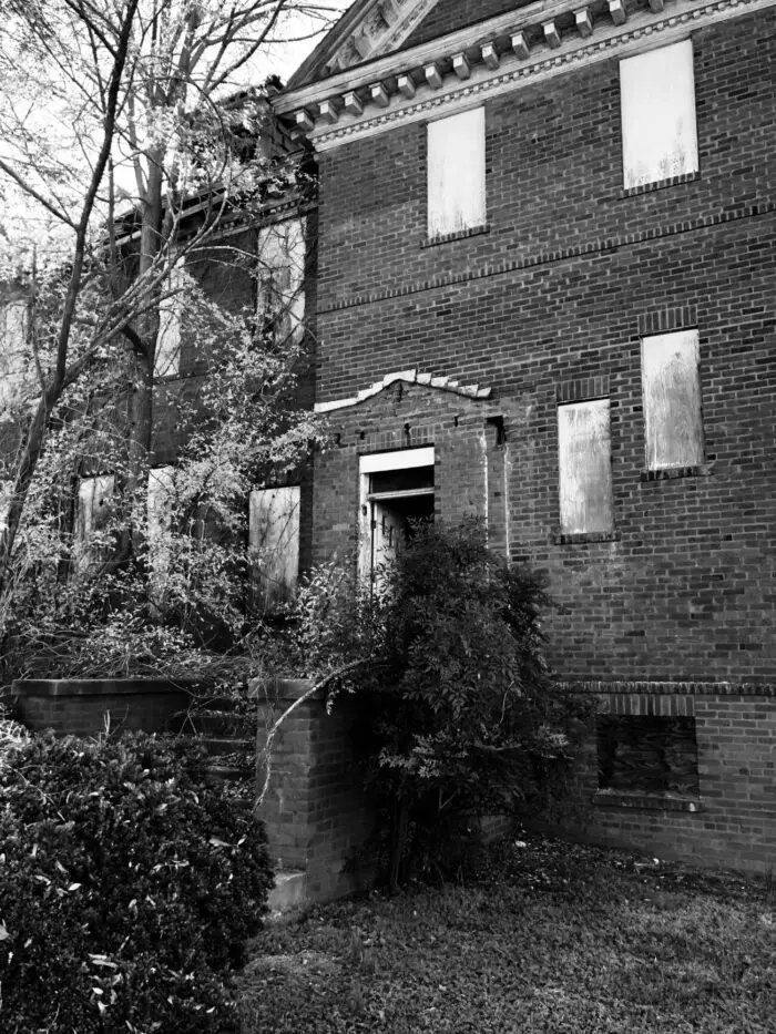 An old brick school building, its windows boarded up.