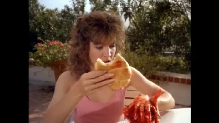 Courtney bites into a hamburger, but then realizes there is a bloodied hand instead of a burger patty