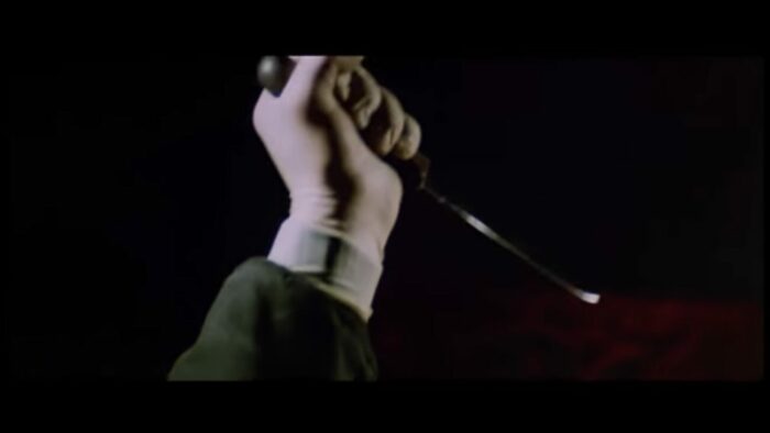 The killer holds a knife in the air, donning a latex glove instead of the usual black leather glove