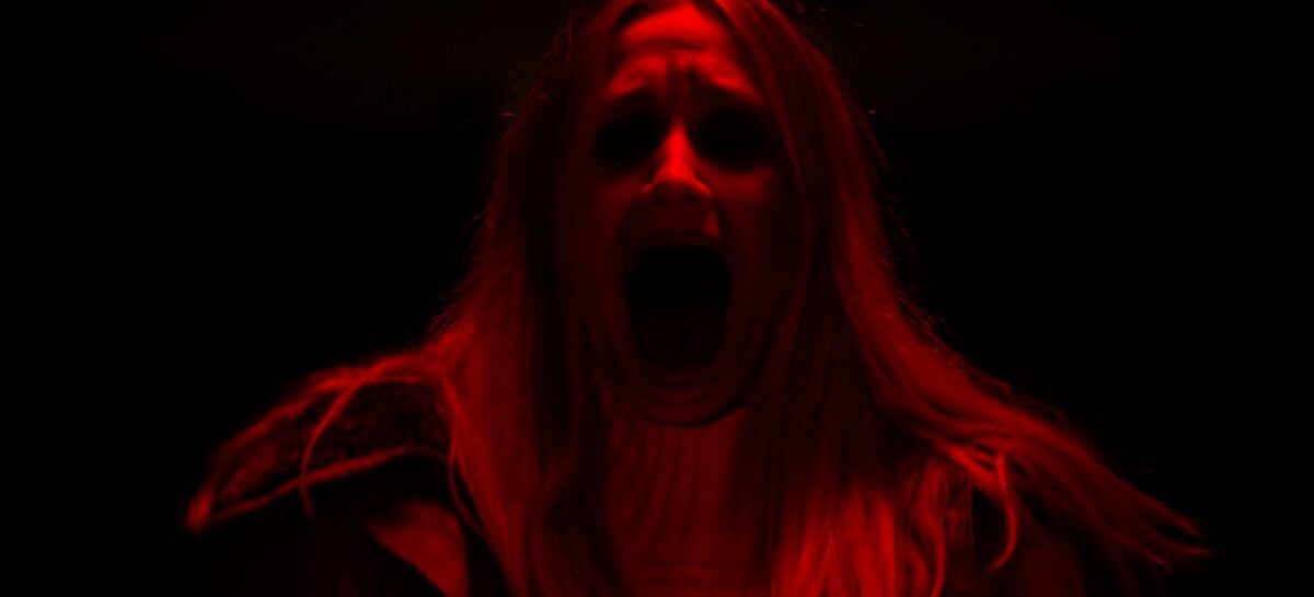 A woman under a red light screaming