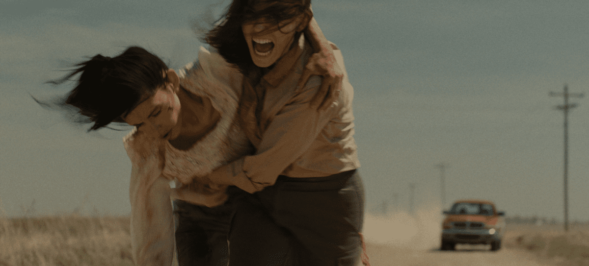 Jamie carries Alex as they travel down a dirt road in Herd
