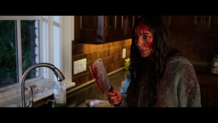 Phoebe is seen covered in blood weilding a cleaver in a kitchen in Here for Blood