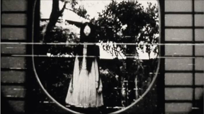 Black and white image of a woman standing in front of trees