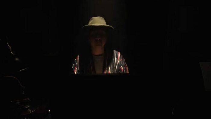 Jay sits at his desk with his lucky hat on, this time the lights go out as a stage light illuminates only him