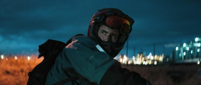 Jack looks off over his left shoulder with his goggles lifted over his helmet,