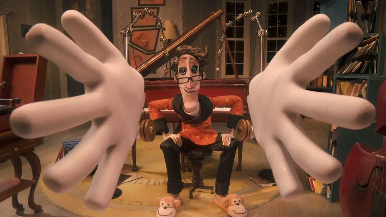 The Other Father, with his button eyes, sits in a room filled with musical instruments, extending his large white gloved hands towards the viewer, wearing an orange and black outfit with monkey slippers