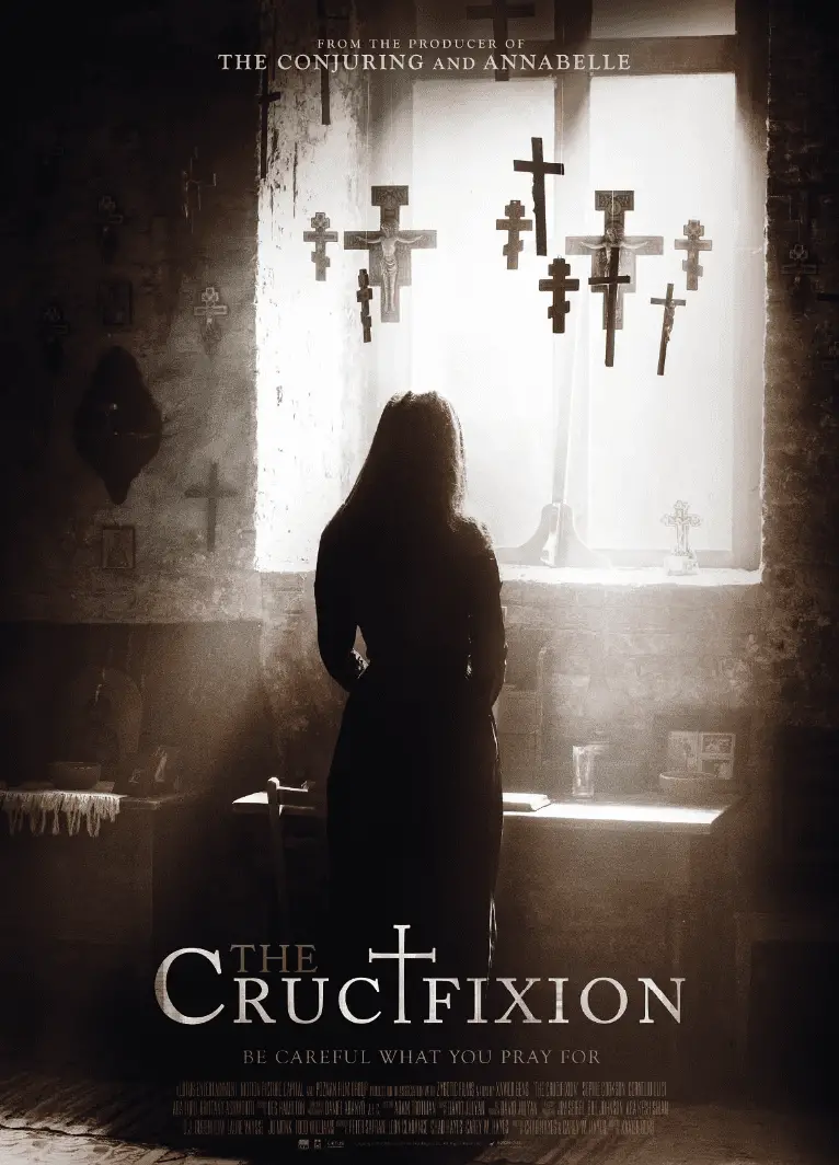 A haunting scene from the movie poster for "The Crucifixion," featuring a shadowy figure of a woman standing in a dimly lit room adorned with numerous crosses. Sunlight filters through a window, casting eerie shadows on the walls. The tagline reads, "Be careful what you pray for," with the title "The Crucifixion" prominently displayed at the bottom.