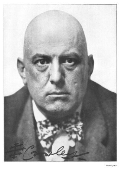 A 1913 photo of famed occultist Aleister Crowley. He is middle aged, bald, and has an intense scowl.