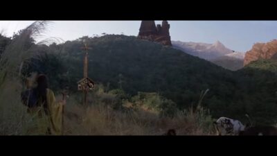 An Eastern European castle sits on top of a hill. A Chinese shaman walks at its base.